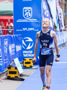 Séverine Guérif à l’arrivée du championnat du monde de duathlon à Târgu Mureș en 2022, les poings serrés de joie et d’émotion après son deuxième titre mondial, symbole de victoire sur le cancer.
