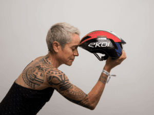 Séverine Guérif en robe noire, posant de profil, tenant son casque de triathlon Ekoi devant son front dans une attitude méditative, symbolisant la réflexion et la performance.