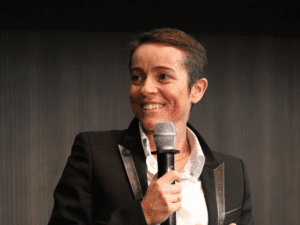 Portrait rapproché de Séverine Guérif tenant un micro et souriant pendant son intervention sur scène, lors du congrès régional des managers à Angers.