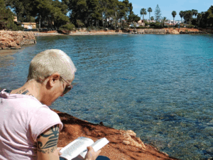 Séverine Guérif lisant au bord de la mer à Ibiza. Moment de détente et de réflexion, symbole d’équilibre entre performance et sérénité.