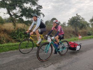 Étape sur la route pendant le tour Stop Cancers Enfants, en gravel avec remorque et un cycliste rencontré sur le parcours.