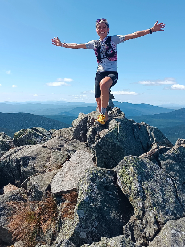 Séverine Guérif en haut d’une montagne lors du championnat du monde XTERRA Trail 2024, bras écartés, rayonnante dans un décor grandiose.