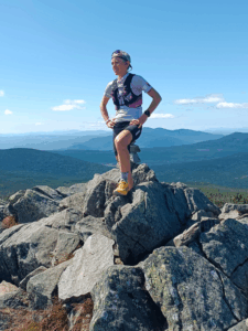 Séverine Guérif sur un sommet rocheux, contemplant les montagnes lors du championnat du monde XTERRA Trail 2024, symbole de sérénité et de liberté.