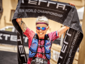 Séverine Guérif sourit en levant le ruban d’arrivée XTERRA au-dessus de sa tête à Gozo en 2026.